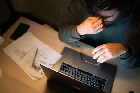 Man looking stressed over laptop and documents
